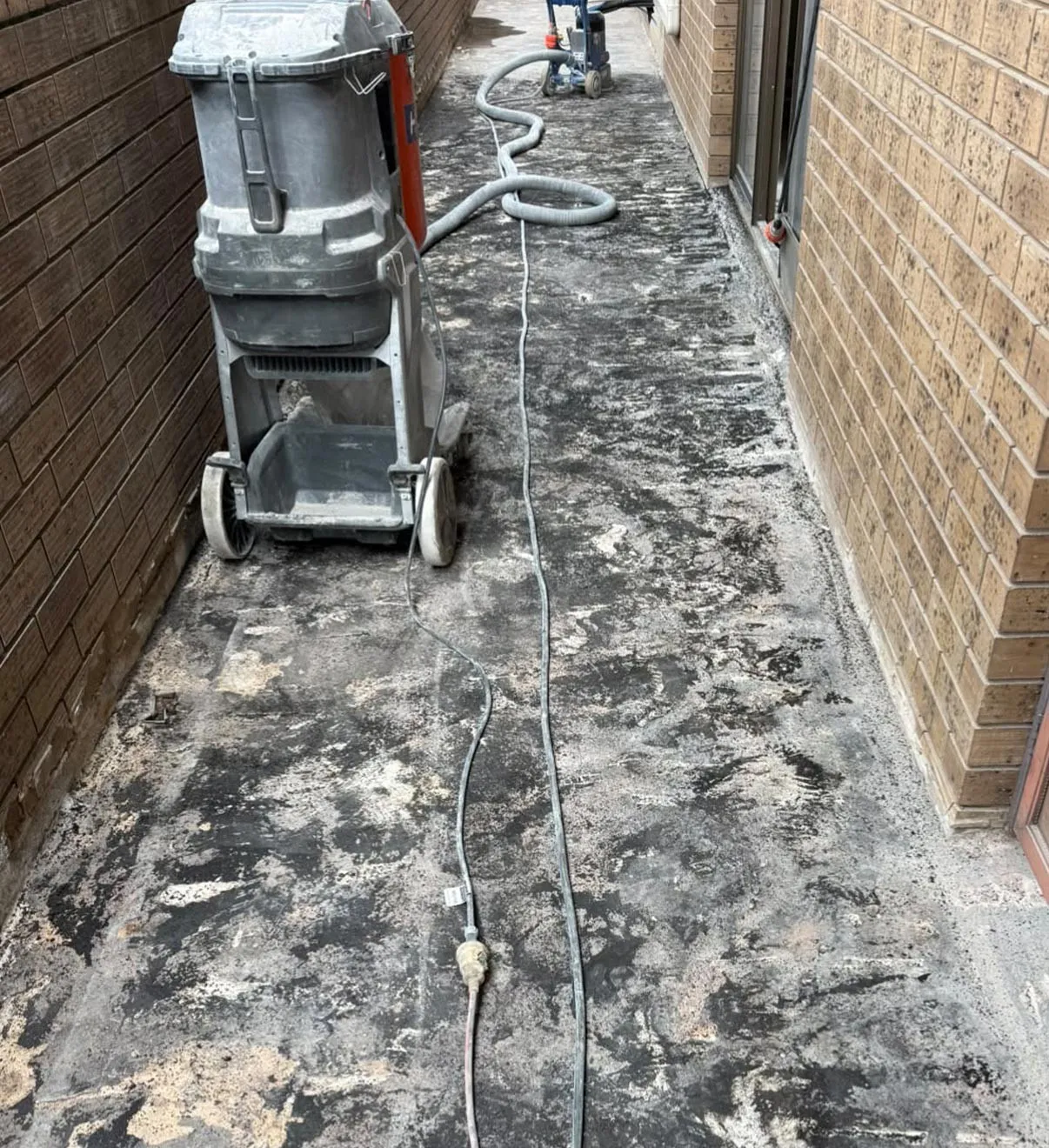 Side path with a worn, patchy old coating before resurfacing